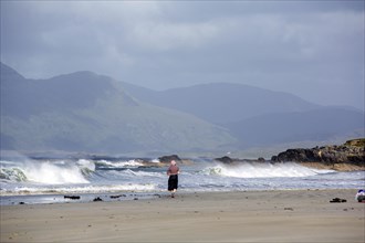 Woman walks Rennvyle Beach along Wild Atlantic way in summer. County Galway