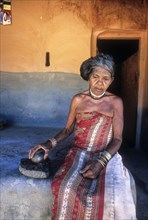 Mudunga tribal old lady sitting in front of the hut