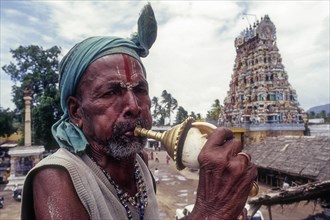Sadhu blowing conch standing infornt of Nataraja temple in Perur near Coimbatore