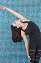 Standing side stretch Yoga pose with a turquoise background