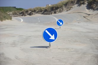 Direction signs on the sandy beach at the beginning of the road