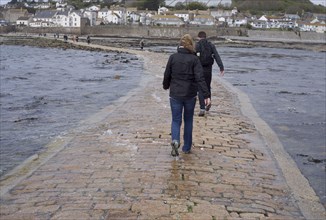 Tourists walking in the sea water covering the man-made causeway from Tidal Island