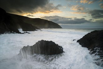 View of swell waves breaking on rocks at dawn