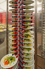 Stacked plates of mixed salad with sliced cheese and sprouts