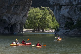 People canoeing on river towards limestone arch