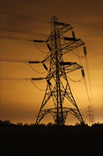 Electricity pylon and overhead power lines illuminated at night by light pollution in the city of Leicester