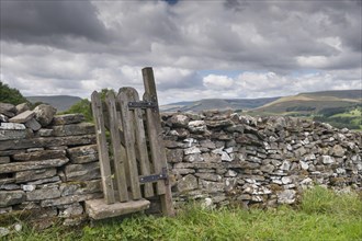 Stiles and gate in dry stone wall on public footpath