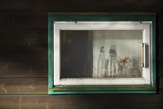 Altes Holzfenster mit zwei Flaschen und Thermometer