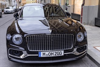 Parked luxury sedan Bentley Flying Spur First Edition in front of fashion shop Boutique Dior