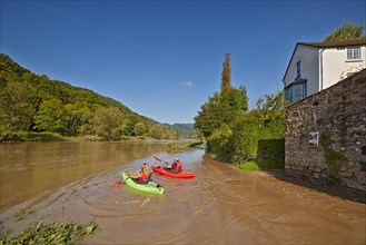 Kayakers on a river flooding at high tide