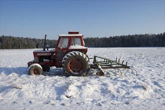 Volvo BM 700 tractor and spring tooth harrow covered with snow