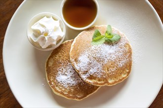 Two pancakes with maple syrup and whipped cream