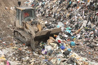 Bulldozer moving rubbish on landfill tip