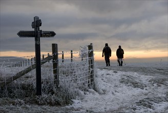 Walkers on frost and snow covered footpath