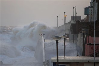 Waves crashing against the seawall of the coastal town during the tidal surge