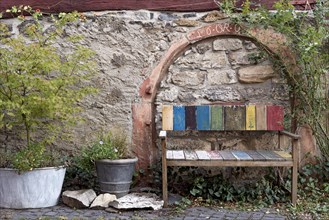 Old colourfully painted faded wooden bench and planter on house wall