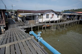 Walkway with blue hookah and huts on stilts in the river