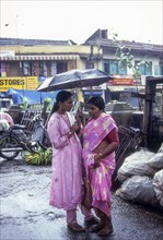 Mother and daughter under umbrella during rainy monsoon season at Ernakulam kochi Cochin