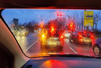 Blick aus dem Auto durch eine regennasse Scheibe mit unklarer Sicht auf den Verkehr am Abend