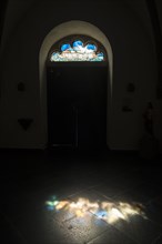 Seitentuer einer Kirche mit kunstvoll verziertem Oberlicht das die Arche Noah mit Taube zeigt