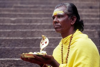A Sadhu sitting on the steps with Naga idol