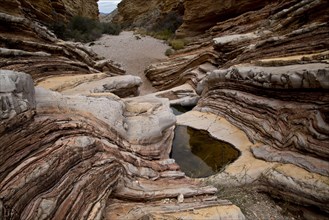 Rock strata and canyon with water in eroded depression on bedrock