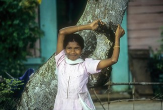 A girl leaning on a tree near backwater of Kuttanad