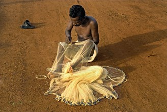 Fishermen mending nets on the beach
