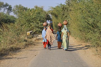 Indian girls carrying water containers on their heads