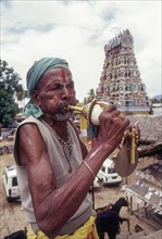 Sadhu blowing conch standing infornt of Nataraja temple in Perur near Coimbatore
