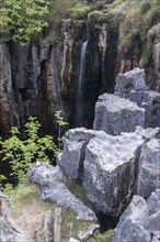 Waterfall flowing into a deep limestone cave