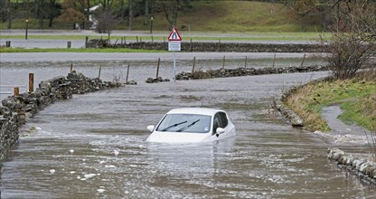 Abandoned car stuck in flood water on road near Hawes