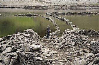 Highland reservoir with low water level and remains of submerged village uncovered after a dry summer