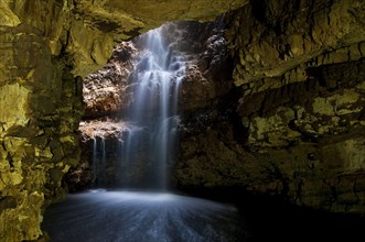 Waterfall flowing through sinkhole into cave