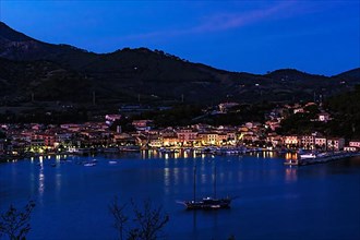 View of Porto Azzurro with illuminated harbour promenade in evening mood during blue hour