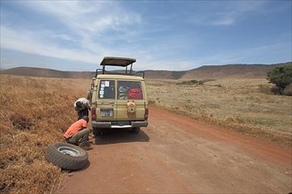Jeep with spare wheel changing tyre due to car breakdown in Ngorongoro Crater