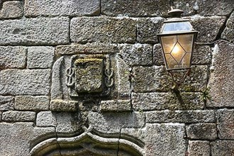 Coat of arms and streetlamp on the facade of an old stone house
