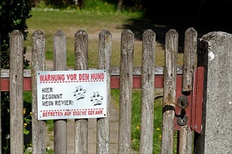 Old garden door with sign warning against dog