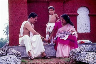 A couple removing the shoes of their kid in order to enter the Ramaswami temple in Thalassery