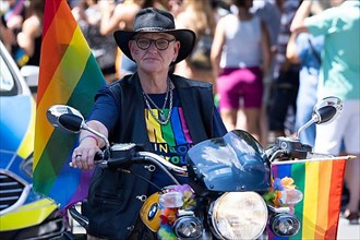 Homosexual man on a motorbike with rainbow flags at the CSD parade