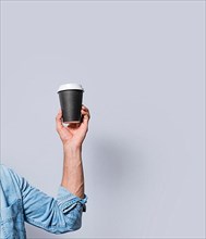 Close up of hand holding a paper cup of coffee. Hand holding a coffee to go on isolated background