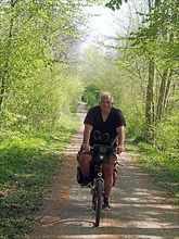 Cyclist with luggage on narrow forest path
