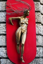 Figure with metal hair on facade as weaving for hairdresser's shop