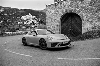 Re-enactment of classic black and white photo of Porsche 911 at historic track of Rally Monte Carlo 1965 with modern supercar sports car Porsche GT3