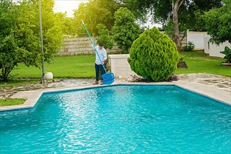 Man cleaning a swimming pool with skimmer