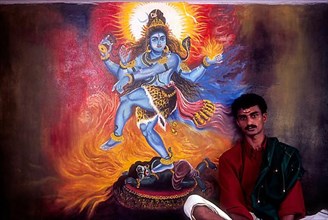 A man sitting near the mural of Lord shiva in Wadakancherry Siva Temple