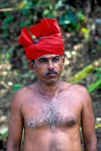 A shirtless man with red turban