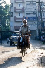 An old man riding bicycle with luggage on the handlebars in Kodungallur
