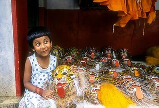 A girl child posing with pulikali mask in her hand in Thrissur or Trichur