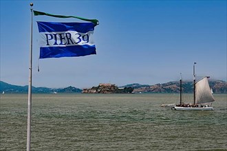 Flag of Pier 39 and historic sailboat in San Francisco Bay